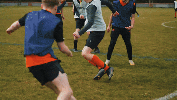 A group of Wilvale Rangers players is on a grass field, wearing practice jerseys and shorts, engaged in an energetic soccer match.