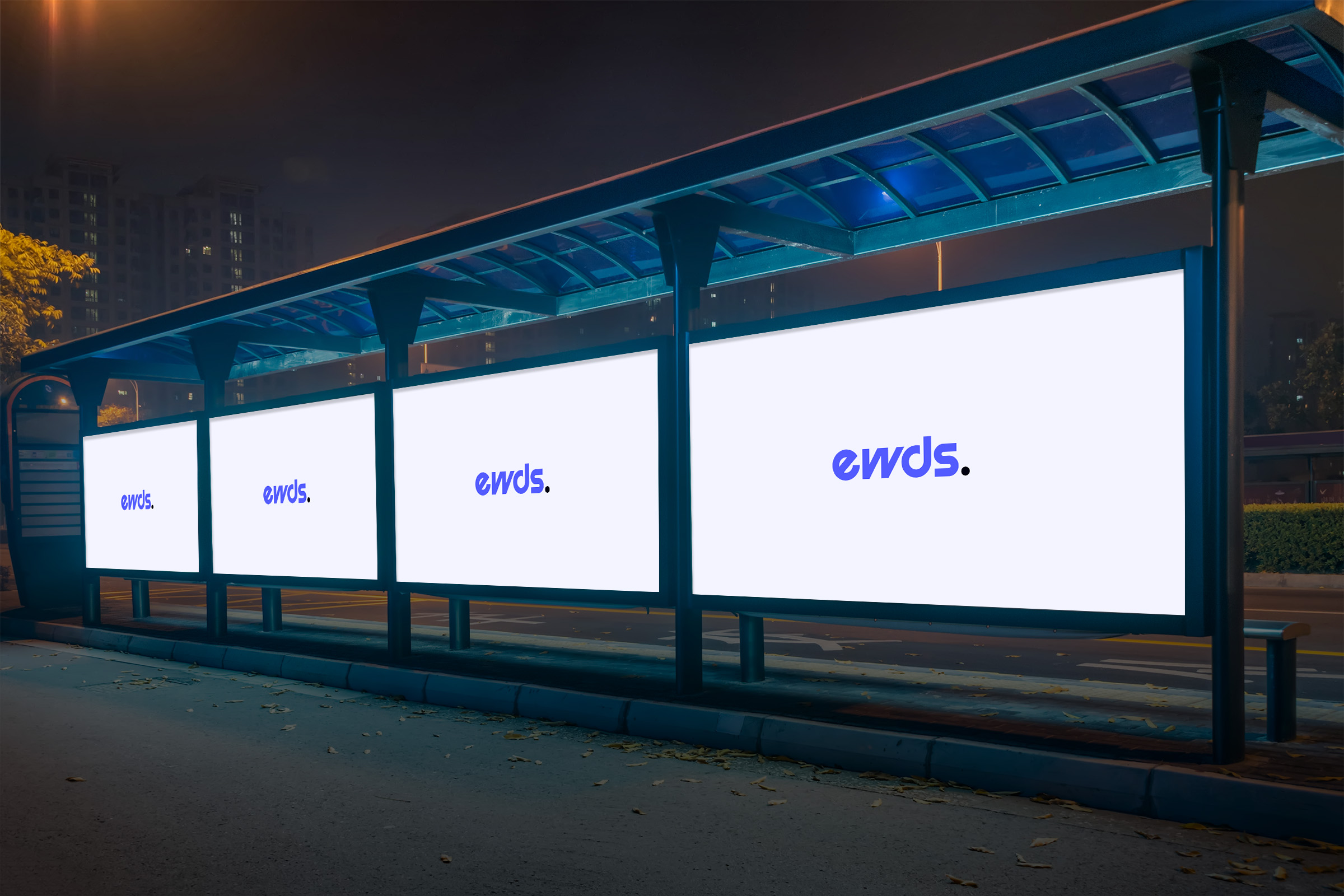 A bus stop at night displaying three illuminated billboards with the word 