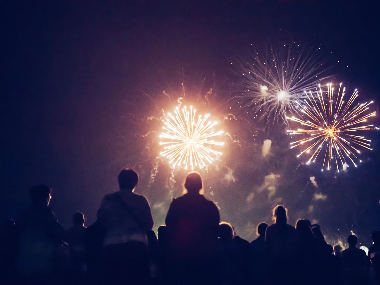 Silhouetted crowd watching colorful fireworks explode in the night sky at the Annual Maldon Firework Display.